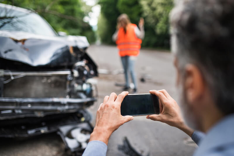 a white male taking cell phone pictures of a car accident